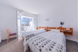 two beds in a room with a window at Hôtel Land'Azur in Mimizan-Plage