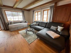 a living room with a black leather couch and a table at Beim Mühltaler in Schleching