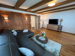 sala de estar con sofá negro y TV en Beim Mühltaler, en Schleching