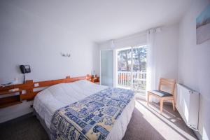 a bedroom with a bed and a window and a chair at Hôtel Land'Azur in Mimizan-Plage