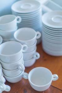 a group of white cups and plates on a table at Hôtel Land'Azur in Mimizan-Plage