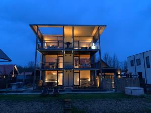 a large house with a lit up facade at night at B&B Veluwemeer, jacuzzi, swim spa, sauna, steam bath and sandy beach in Biddinghuizen