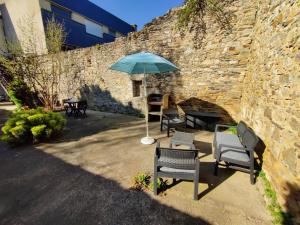 a patio with chairs and an umbrella next to a brick wall at Appartement T2 "Le Cocoön" rez-de-jardin au calme in Vitré