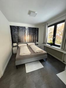 a bedroom with a large bed and two windows at Ferienwohnungen Rothaarglück in Schmallenberg