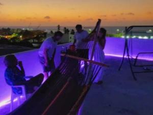 a group of people standing on a rooftop with purple lights at Amiri in Puerto Colombia