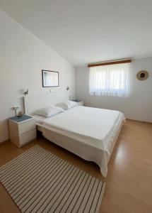 a bedroom with a large white bed and a window at Apartments Dubravka in Medulin