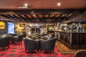 - un bar avec des fauteuils en cuir et un mur en pierre dans l'établissement The Kings Head Inn, à Llandovery