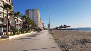 einen Bürgersteig neben einem Strand mit Palmen und Gebäuden in der Unterkunft Arteg Apartments - Comfort in Durrës