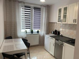 een keuken met witte kasten en een tafel met stoelen bij Sweet apartament in Tarnowskie Góry