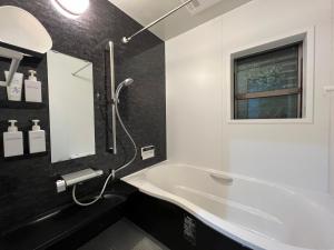 a bathroom with a tub and a sink and a window at Guesthouse Kaede Annex in Nara