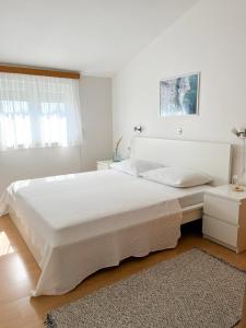 a white bedroom with a large bed and a rug at Apartments Dubravka in Medulin