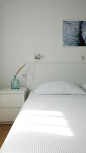 a bedroom with a white bed and a picture on the wall at Apartments Dubravka in Medulin