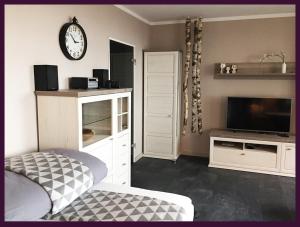 ein Wohnzimmer mit einem TV und einer Uhr an der Wand in der Unterkunft Apartment EULE - Gute-Nacht-Braunschweig in Braunschweig