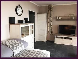 a living room with a tv and a clock on the wall at Apartment EULE - ruhige Innenstadtlage mit Balkon in Braunschweig