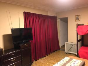 ein Schlafzimmer mit einem roten Vorhang und einem TV in der Unterkunft Ballivian in Tarija