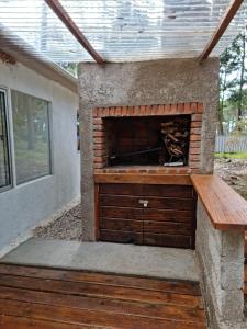 una chimenea de piedra en un patio con un banco de madera en Ohana2 Punta Ballena, en Punta del Este