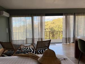 a bedroom with two chairs and a large window at Monte Gois Country House e Spa in Curvatos