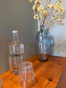 a wooden table with a vase and a bottle and glasses at Monte Gois Country House e Spa in Curvatos