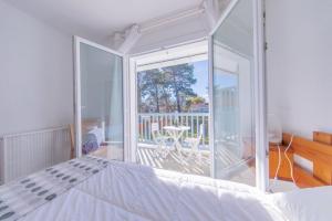 a bedroom with a bed and a view of a balcony at Hôtel Land'Azur in Mimizan-Plage