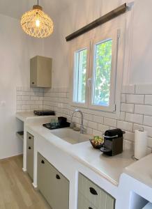 a white kitchen with a sink and a window at Batsi Seaside Apartment in Batsi