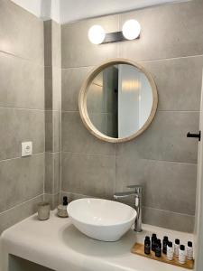 La salle de bains est pourvue d'un lavabo blanc et d'un miroir. dans l'établissement Batsi Seaside Apartment, à Batsi