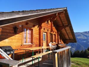 eine Blockhütte mit einem Tisch und einem Grill auf einer Terrasse in der Unterkunft Chalet mit Alpenambiente Axalp in Brienz