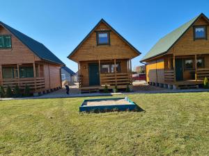 two log homes with a pool in front of them at Morska Fala in Jezierzany