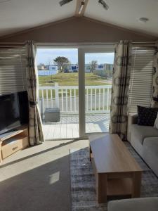 a living room with a couch and a tv at RICK'S RETREAT static caravan near the beach with free wifi in Lossiemouth