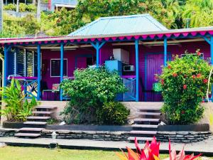 una casa rosa y azul con algunas plantas y flores en Le Nid Tropical, en Bouillante