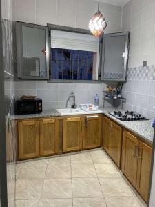 - une cuisine avec des placards en bois et un évier dans l'établissement Bizerte maison en plein cœur de la médina, à Bizerte