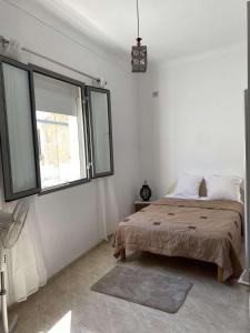a white bedroom with a bed and a window at Bizerte maison en plein cœur de la médina in Bizerte