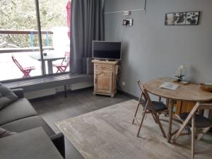 a living room with a couch and a table with a television at Studio au cœur des Volcans d Auvergne - Murol in Murol