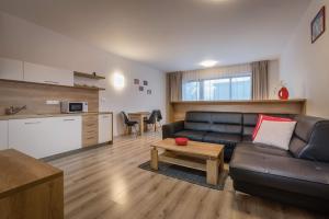 a living room with a black leather couch and a table at Horský apartmán Hrebienok A203 in Smokovce