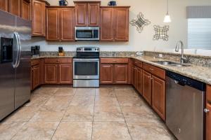 una cocina con armarios de madera y electrodomésticos de acero inoxidable en 8 Bedroom Estate Near Disney World, en Davenport