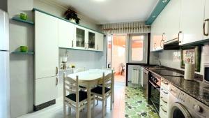 a kitchen with a table and some chairs in it at Piso Céntrico Nati Con Parking Incluído in O Grove