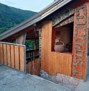 a log cabin with a porch with a basket on it at Popović na Drini in Bajina Bašta
