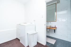 W białej łazience znajduje się umywalka i lustro. w obiekcie Apartment on Robert Rd w mieście Raglan
