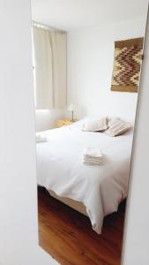 um quarto com uma cama branca e pisos em madeira em Departamento céntrico con vista al lago em San Carlos de Bariloche