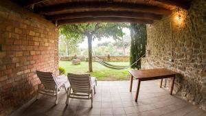 un patio con sillas, una mesa y una hamaca en Cal Planell Casa Rural, en Vall-Llebrera