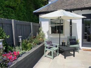a patio with a table and an umbrella and chairs at Seaview Cottage in Ascog