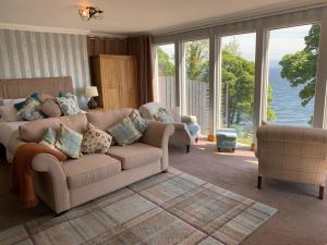 a living room with a couch and large windows at Seaview Cottage in Ascog