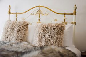 a bed with white pillows and a gold headboard at Salt Life Cottage in Brighton & Hove