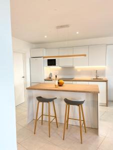 a kitchen with white cabinets and a counter with stools at Feel Tenerife Suites - Adults ONLY in La Matanza de Acentejo