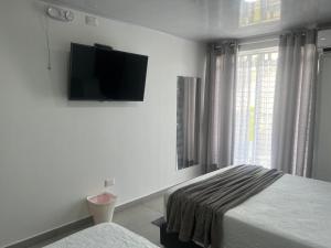 a bedroom with two beds and a tv on the wall at Summer Breeze in San Andrés