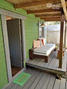 a porch with a bed and a door on a deck at Cabañas Techarí in Punta Del Diablo