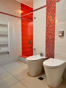 a bathroom with a toilet and a red wall at Casa Boutique LUNA LUCIA in Monte Hermoso