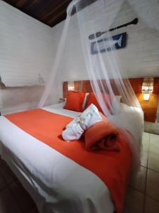 1 dormitorio con 1 cama con almohadas de color naranja y blanco en Villas de Tibau, en Pipa