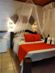 a bedroom with a large bed with red pillows at Villas de Tibau in Pipa