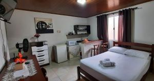 a bedroom with a white bed and a kitchen at Casa de hóspedes aconchegante in Pinhais