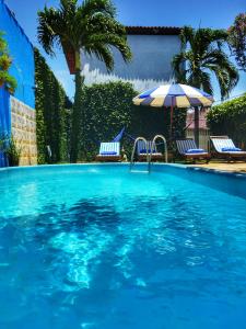 a swimming pool with two chairs and an umbrella at Villas de Tibau in Pipa